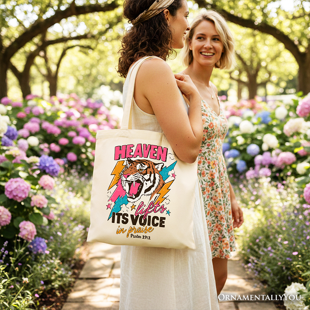 Cream tote bag carried outdoors with tiger artwork and colorful Christian message print.