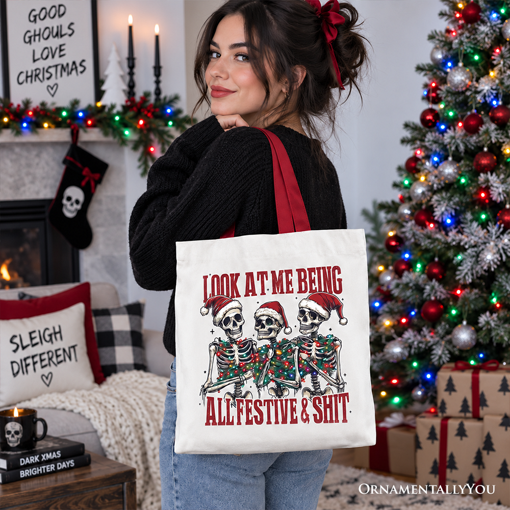 White cotton tote bag with skeleton holiday graphic and red text; held over denim jacket