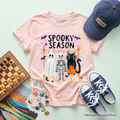 Light pink kids spooky season graphic T-shirt with colorful haunted characters print