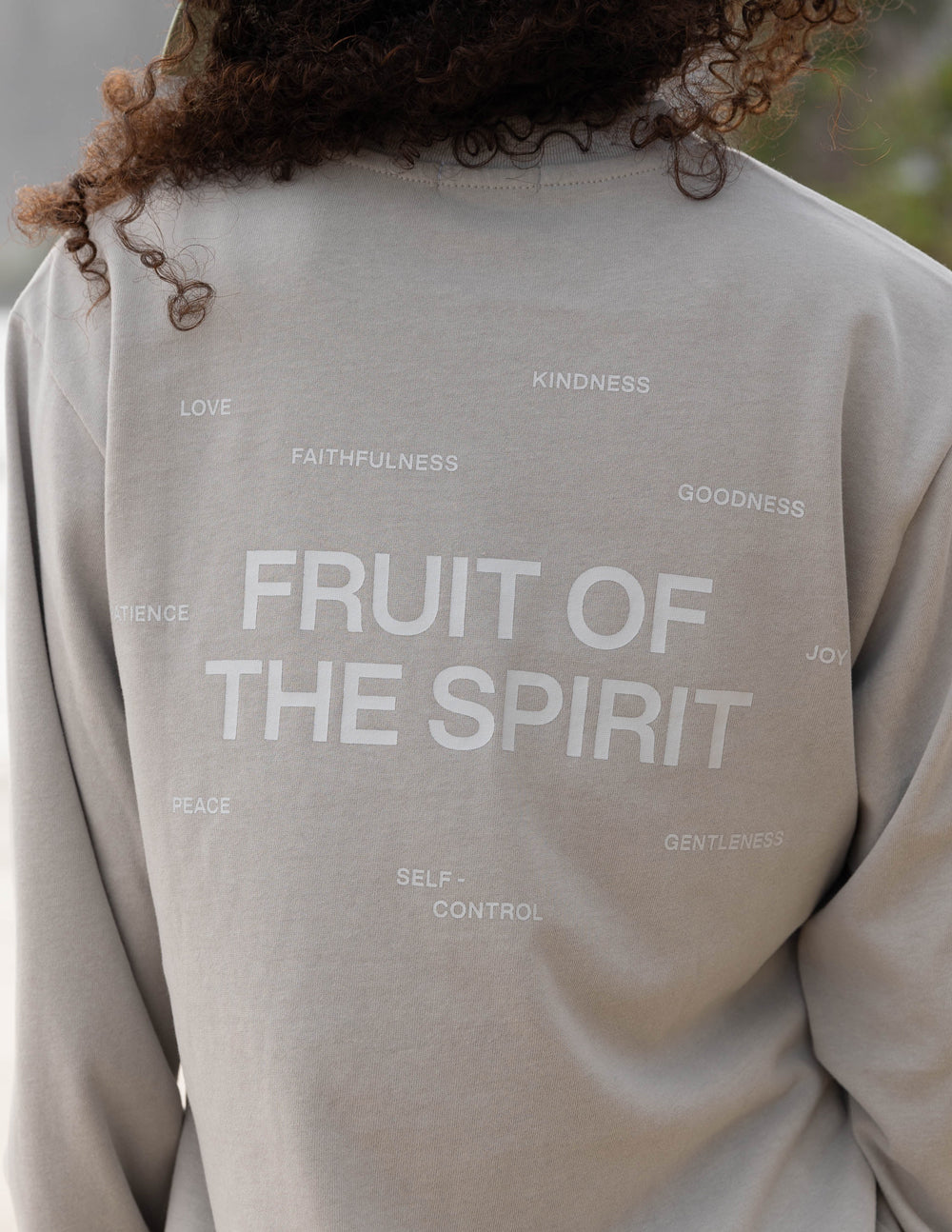 Back view close-up of grey long-sleeve T-shirt with large “FRUIT OF THE SPIRIT” print.