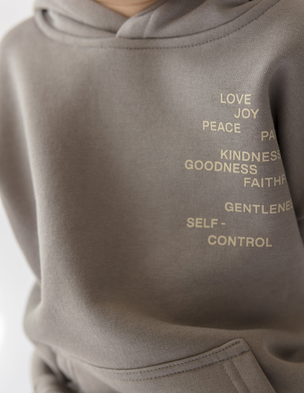 Kids gray hoodie sleeve close-up with printed words in light lettering