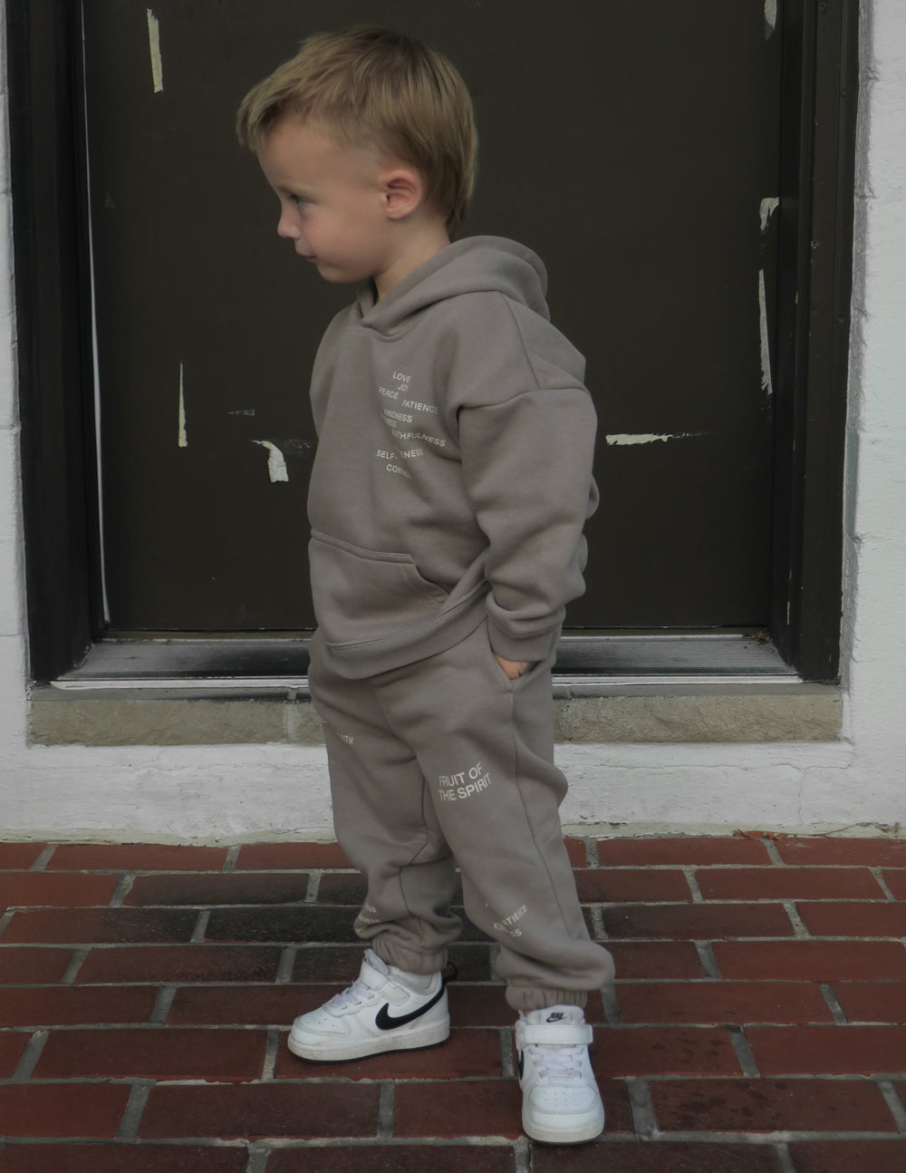 Kids gray hoodie with hood and chest graphic, side view with jogger pants