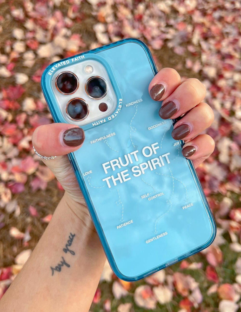 Blue Fruit of the Spirit phone case held to camera; clear back with camera cutouts