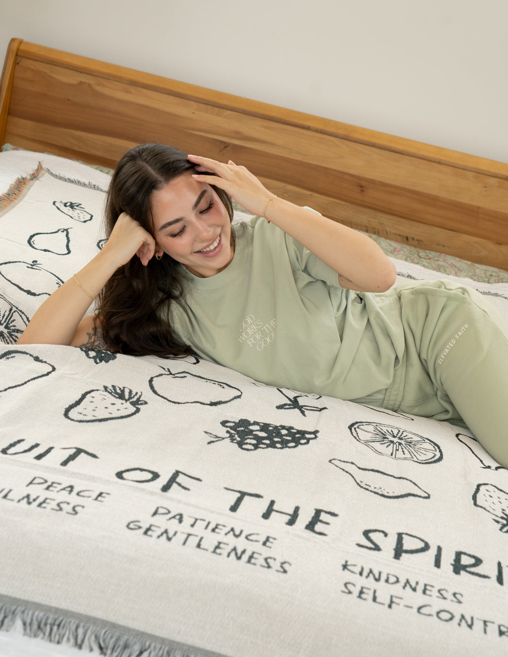 Cream throw blanket with black fruit icons and scripture-style word text, fringe