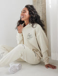 Unisex hoodie in off-white with hood, front kangaroo pocket, and small chest logo text