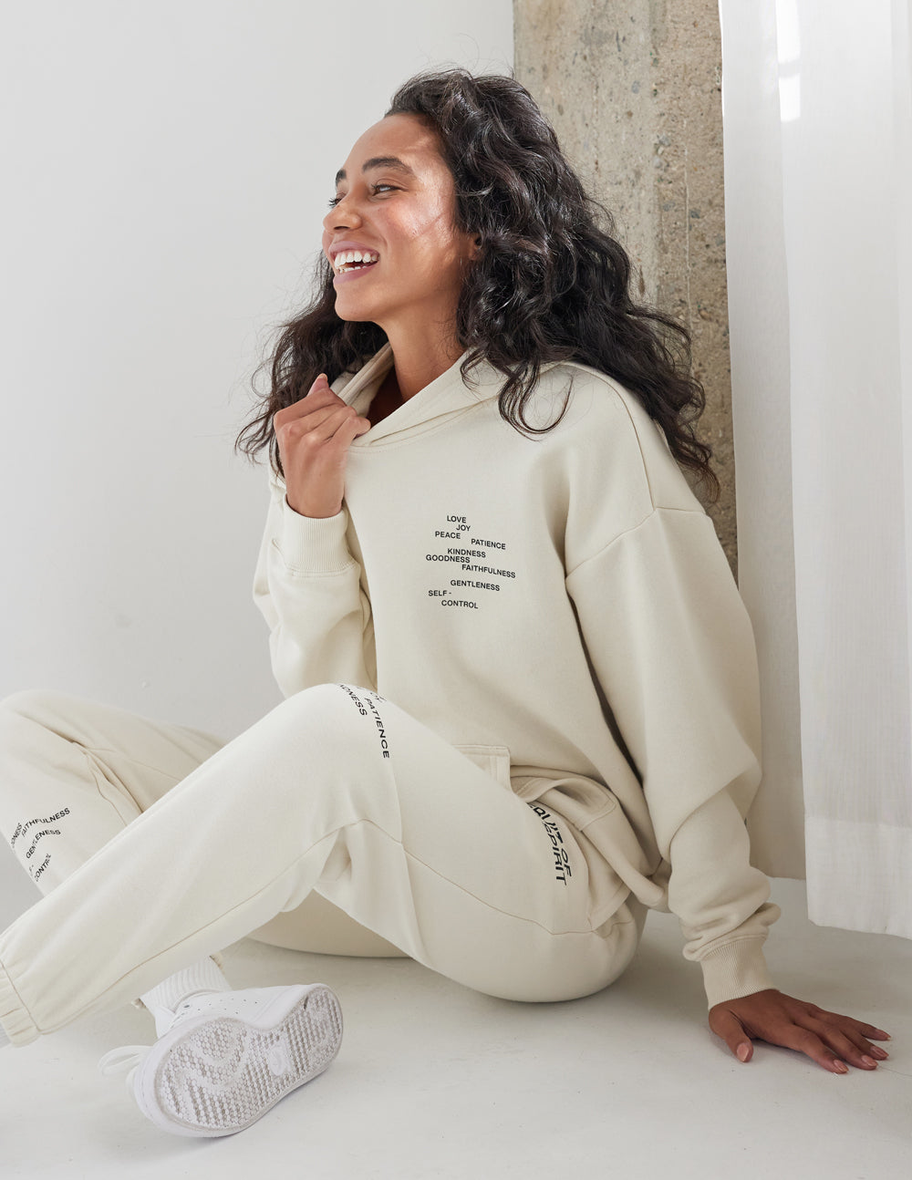 Unisex hoodie in off-white with hood, front kangaroo pocket, and small chest logo text