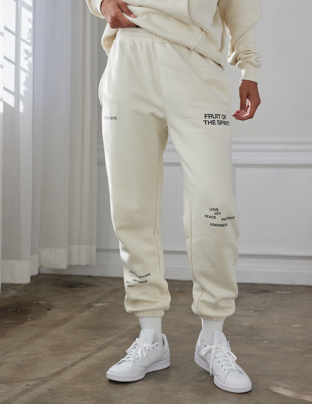 Cream unisex sweatpants with relaxed fit, cuffed hems, and side leg print