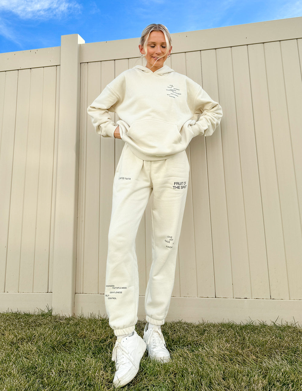 Cream unisex sweatpants with logo graphic and printed message on pant legs