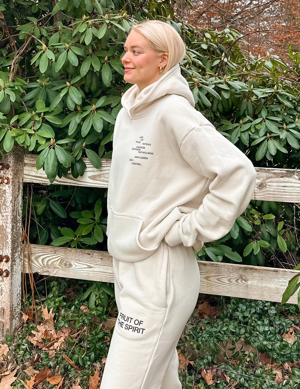 Cream unisex sweatpants with vertical thigh text and relaxed cuffed hems