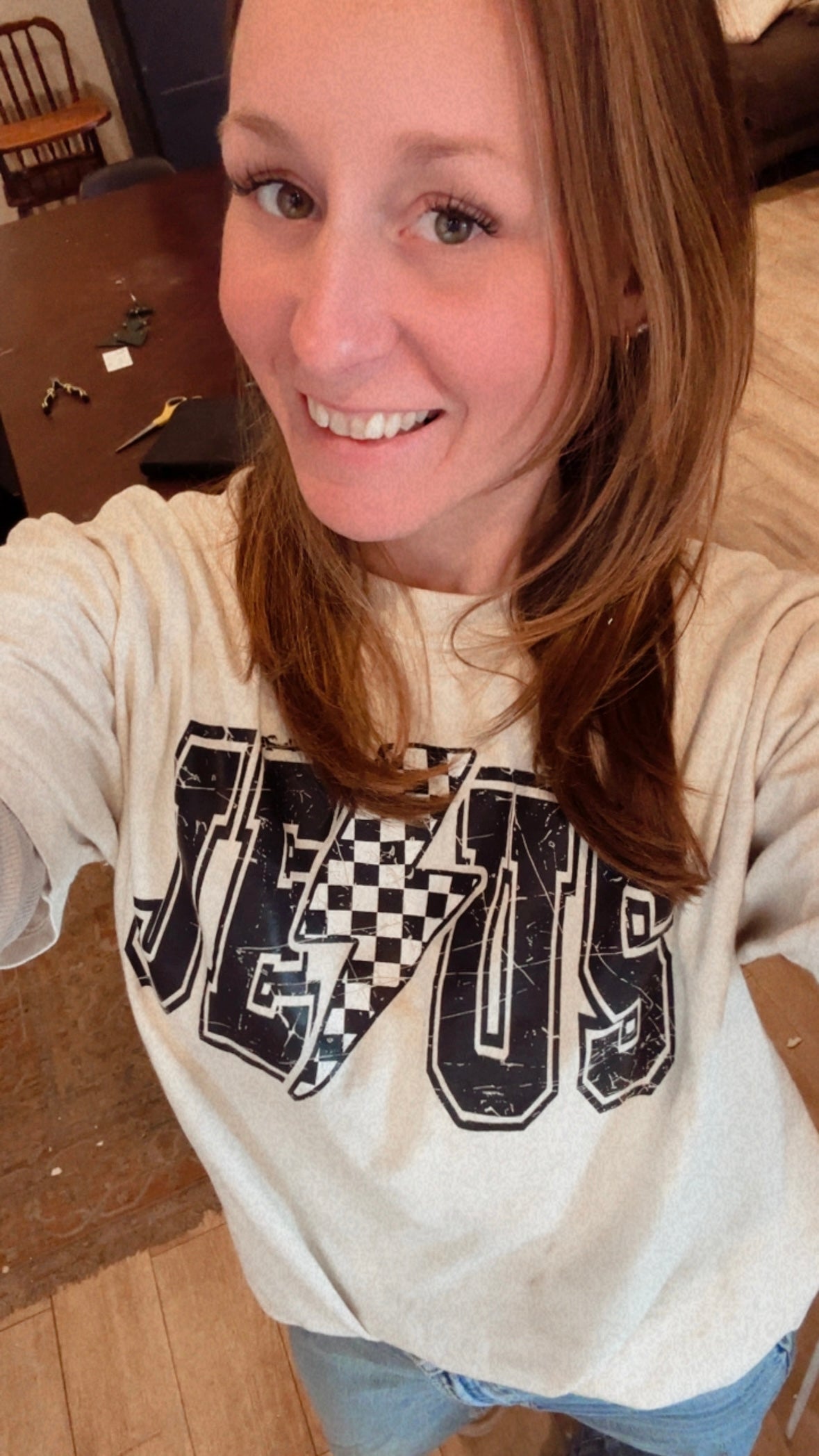 Cream T-shirt on person with checkered lightning bolt logo and 'Jesus' lettering
