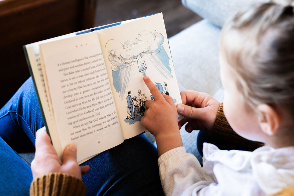 Christmas book open to an illustrated page with a pointing figure