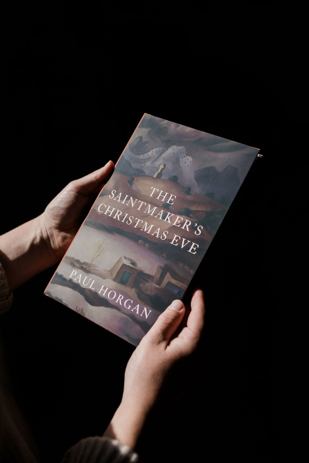 Book held in hands, illustrated cover with gold title text
