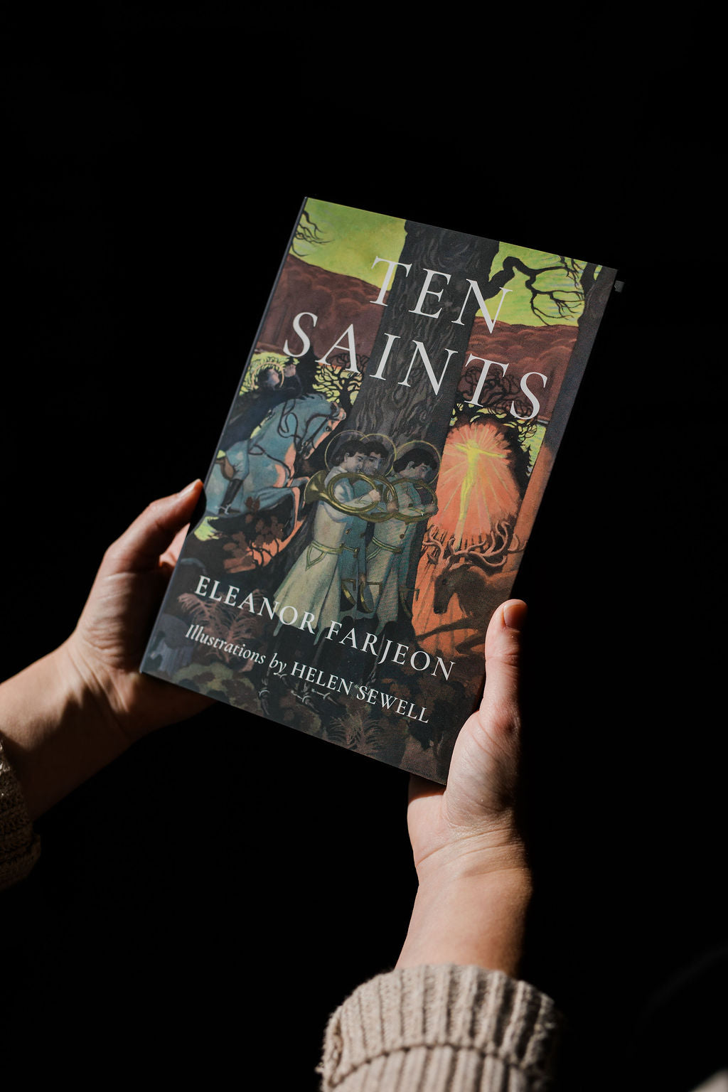 Saints book held in hands; cover shows illustrated scenes and title lettering