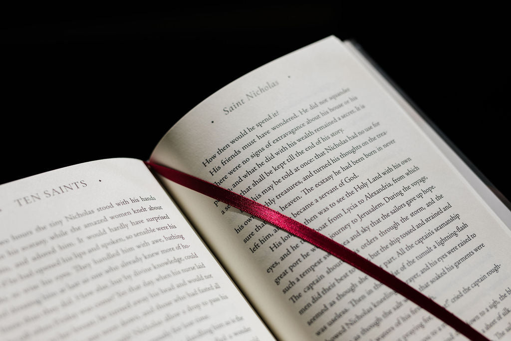 Open Saints book with paragraphs of text and red ribbon bookmark