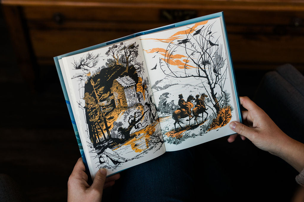 Hardcover book open to two illustrated pages with white layout and blue border