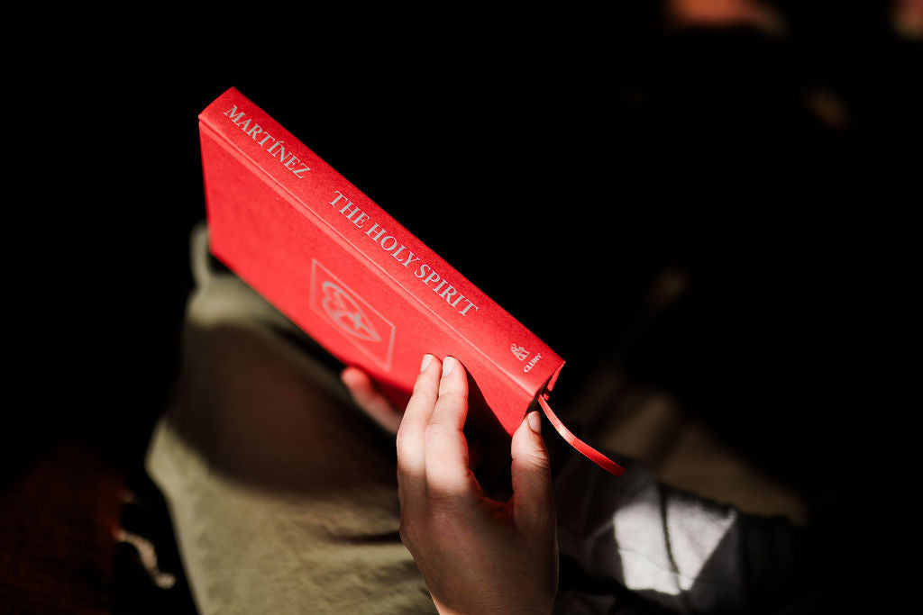 Holy Spirit book with red cover and title, held at an angle by hands