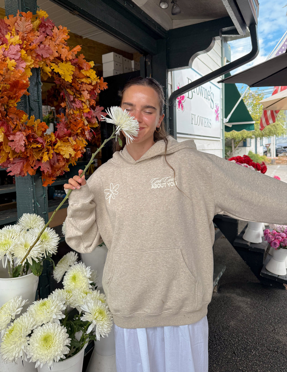 Light beige unisex hoodie back graphic with "ABOUT YOU" text and flower