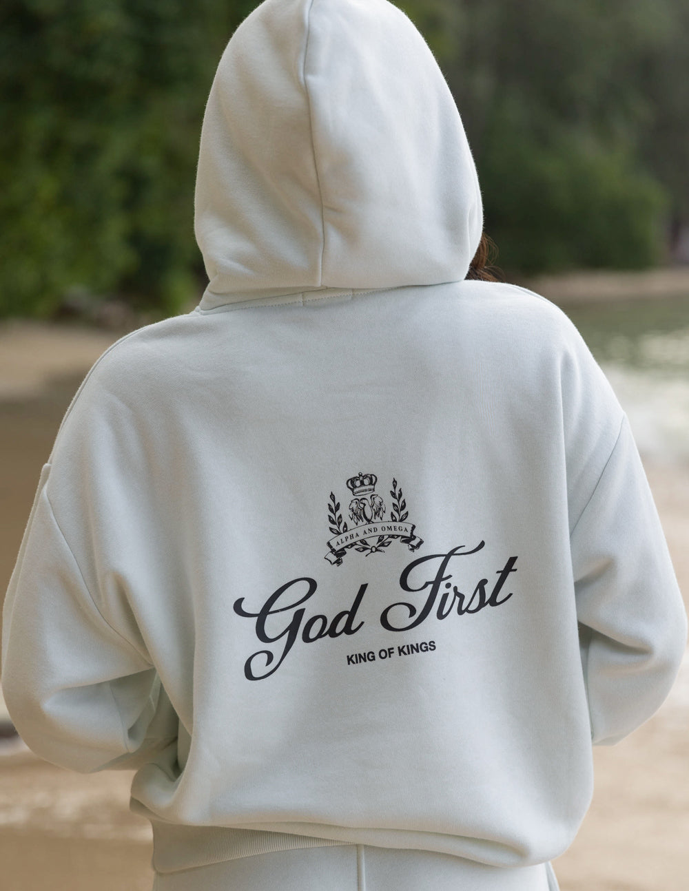 Unisex light cream hoodie, back print shows God First crown and King of Kings text
