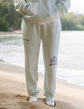 Unisex sweatpants, off-white, “ELEVATED FAITH” print on left thigh and crest on leg