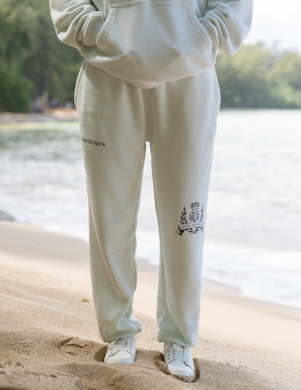 Unisex sweatpants, off-white, “ELEVATED FAITH” print on left thigh and crest on leg