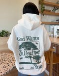 White unisex hoodie with large green back graphic reading God Wants To Heal You