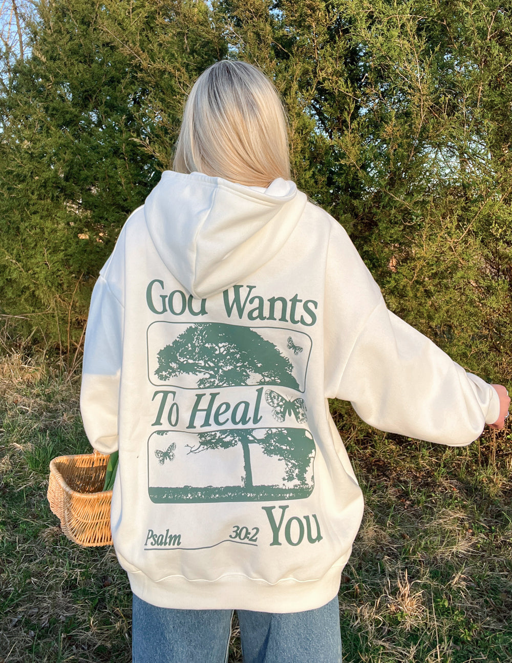 White unisex hoodie with large green back graphic reading God Wants To Heal You