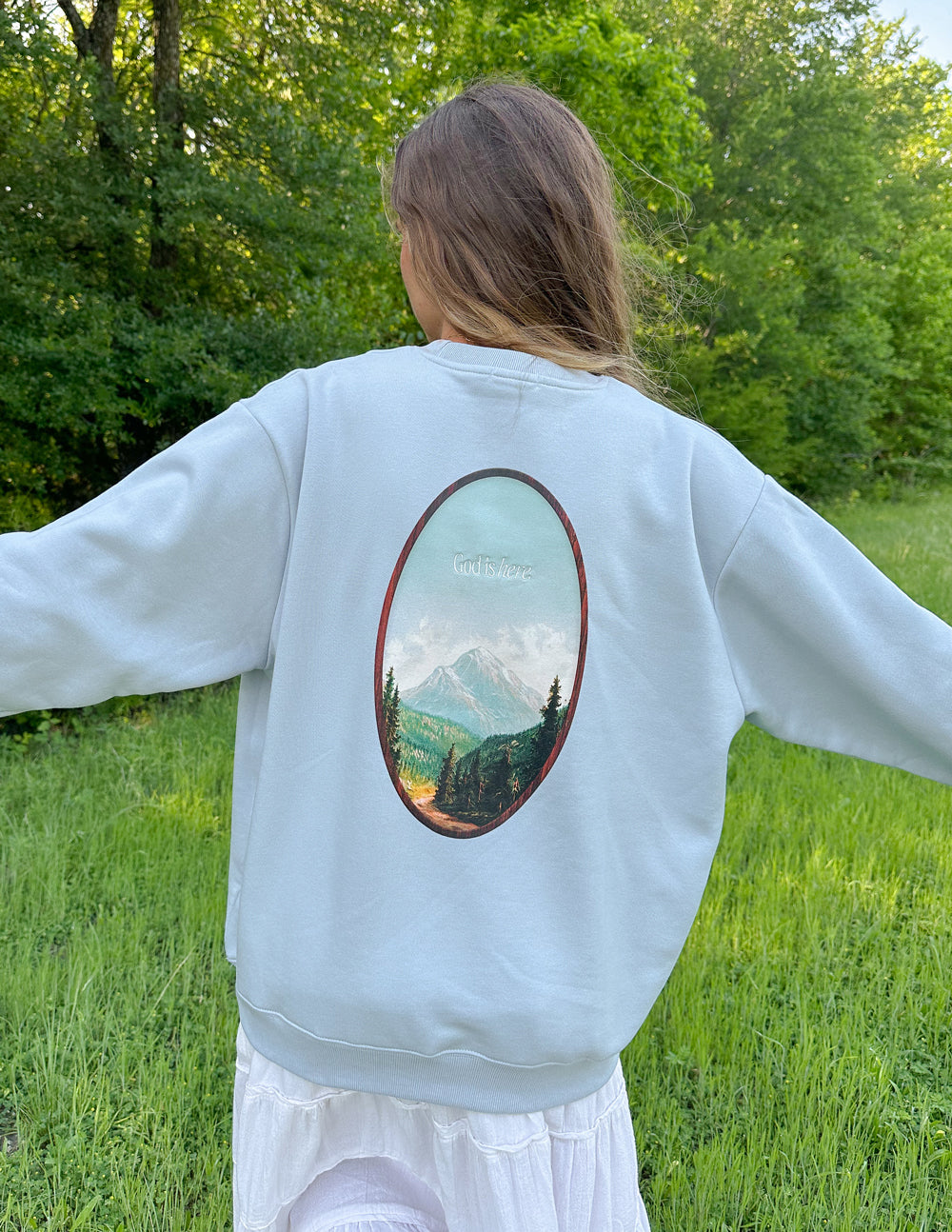 Light blue unisex crewneck sweatshirt with oval landscape graphic centered on back