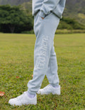 Light blue unisex sweatpants with vertical 'God is here' print on one leg