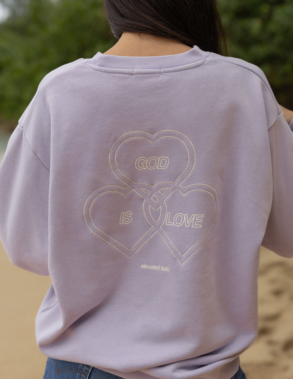 Lavender crewneck sweatshirt back features heart outlines with “GOD IS LOVE”