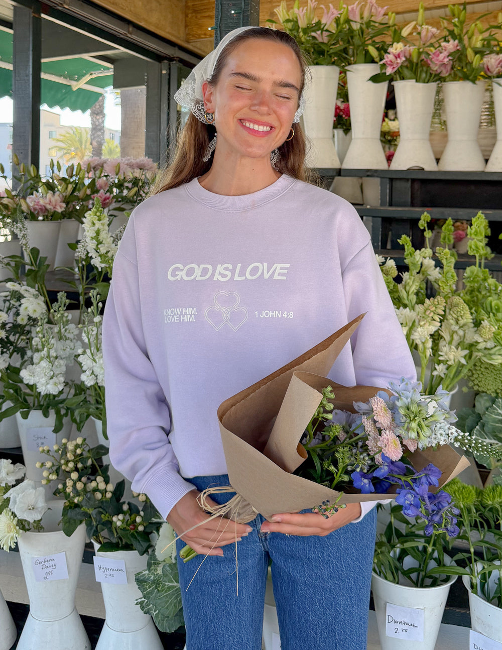 Lavender unisex crewneck sweatshirt front text “GOD IS LOVE” with heart graphic