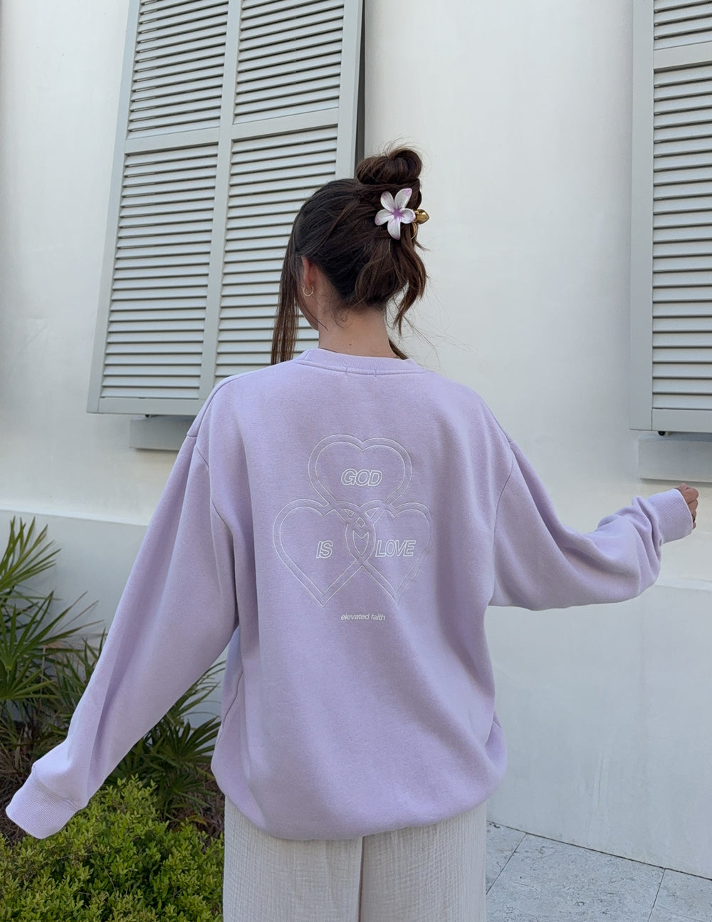 Lavender crewneck sweatshirt viewed from back with heart-and-text graphic