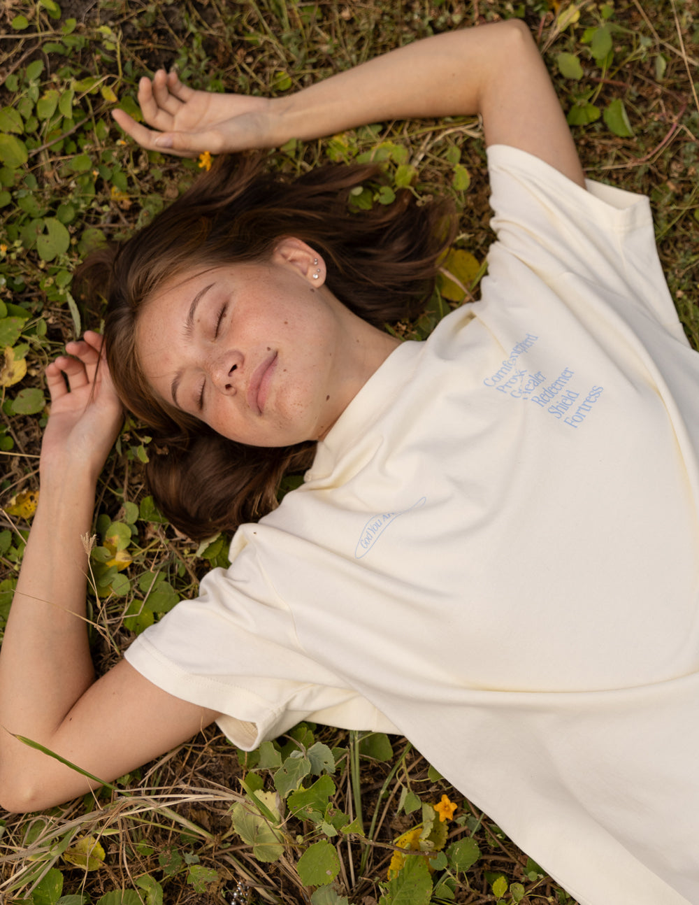 Cream unisex short-sleeve T-shirt with small blue text graphic on sleeve