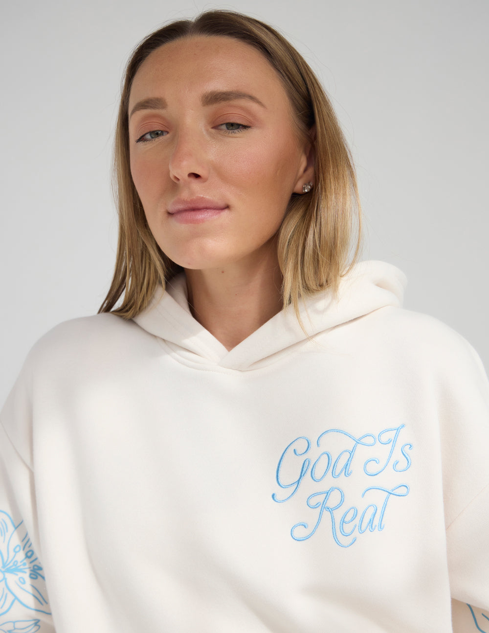 Unisex off-white hoodie with blue “God Is Real” front chest print and hood