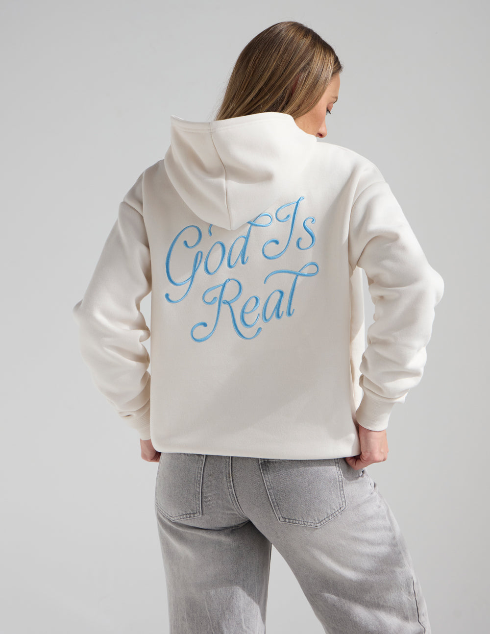 Unisex off-white hoodie, back view, blue “God Is Real” text and hood