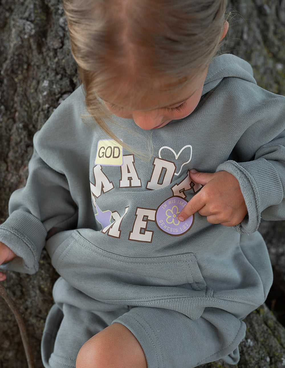 Kids sage green hoodie with "God Made Me" graphic and ribbed cuffs.