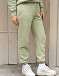 Light green unisex sweatpants with drawstring waist and front logo print