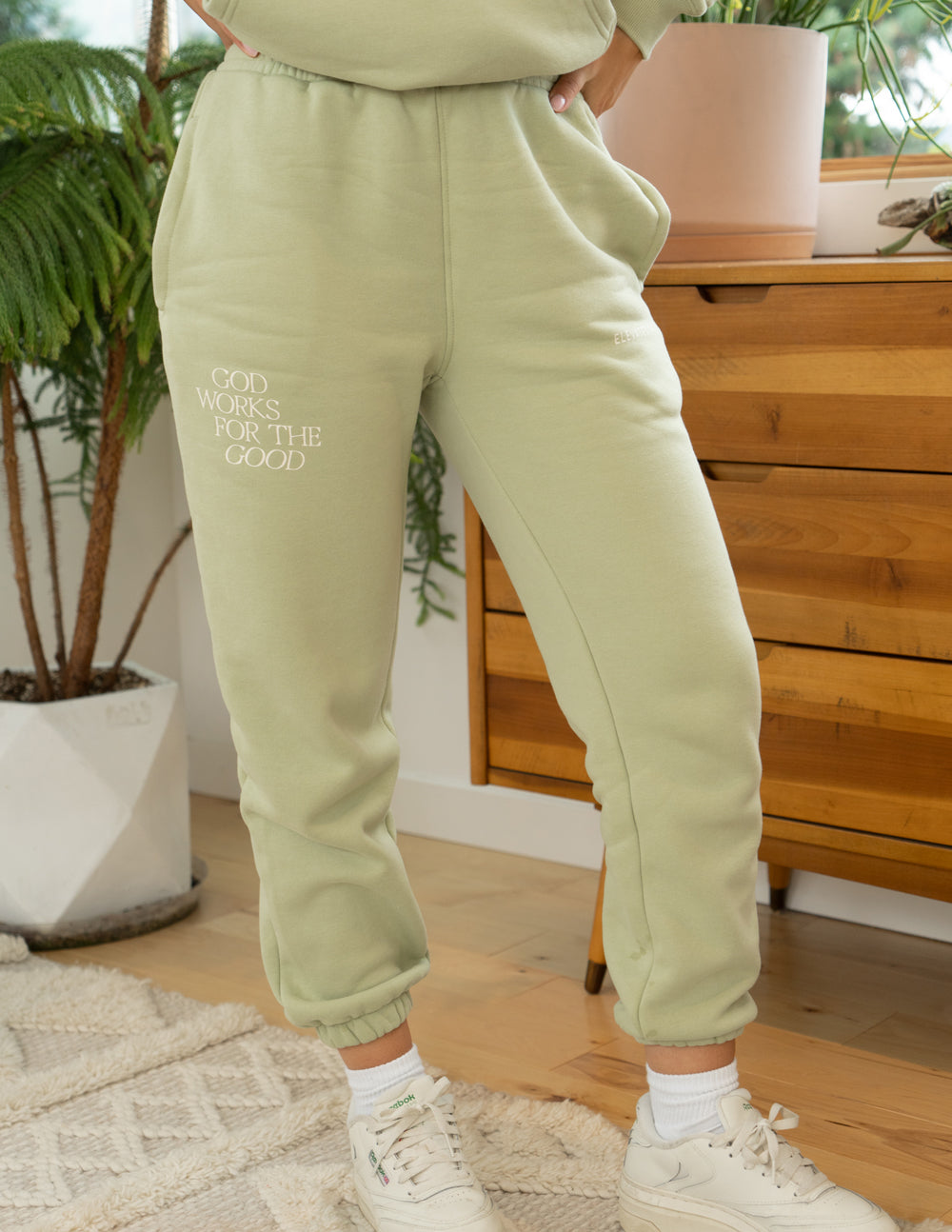 Light green unisex sweatpants with cuffed hem and printed text on leg