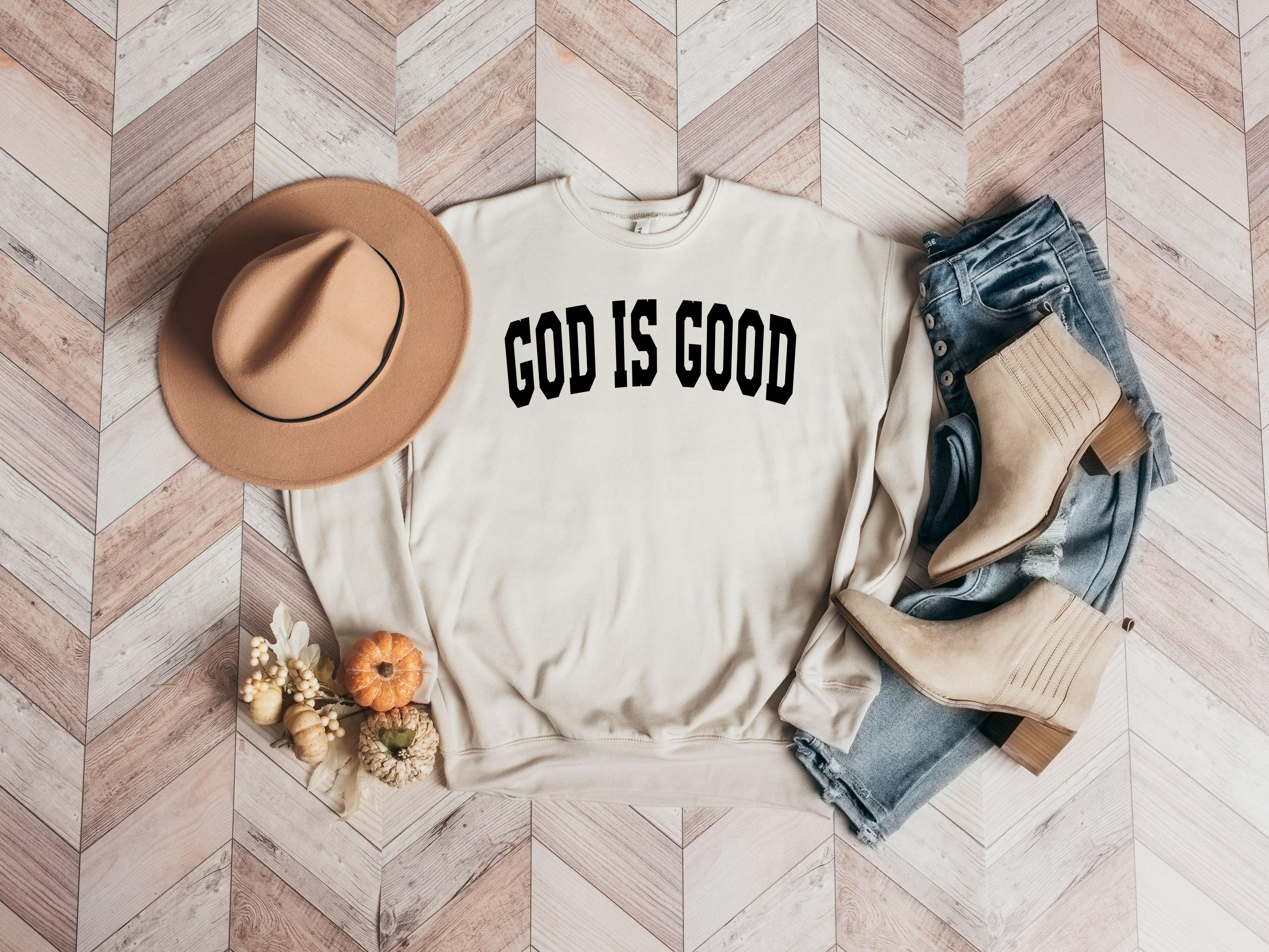 Unisex crewneck sweatshirt in cream with "GOD IS GOOD" front graphic