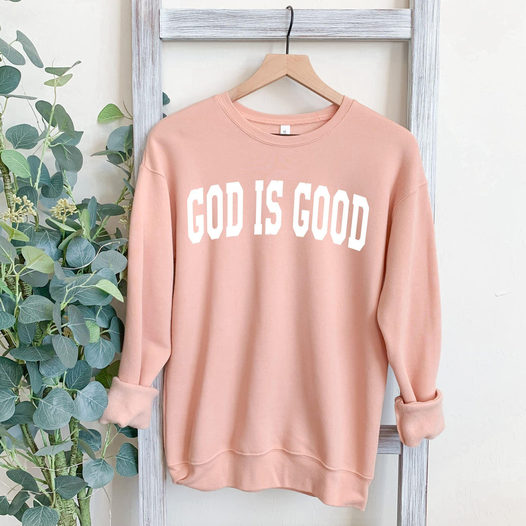 Unisex crewneck sweatshirt in blush pink with "GOD IS GOOD" front graphic