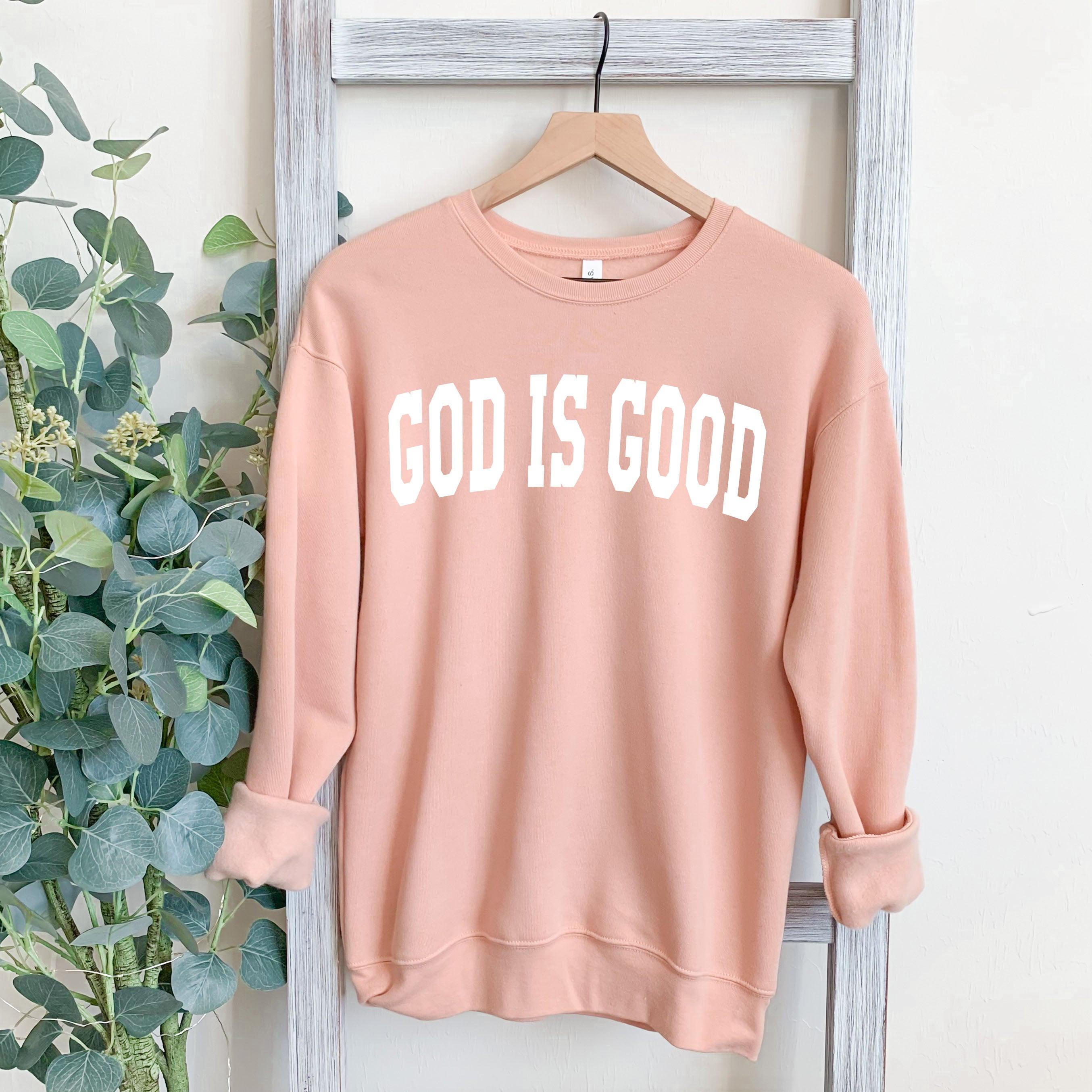 Unisex crewneck sweatshirt in blush pink with "GOD IS GOOD" front graphic