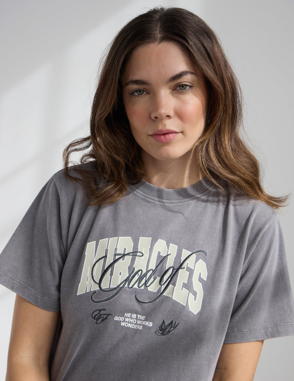 Cropped gray women’s tee showing the “Miracles” chest graphic and small text