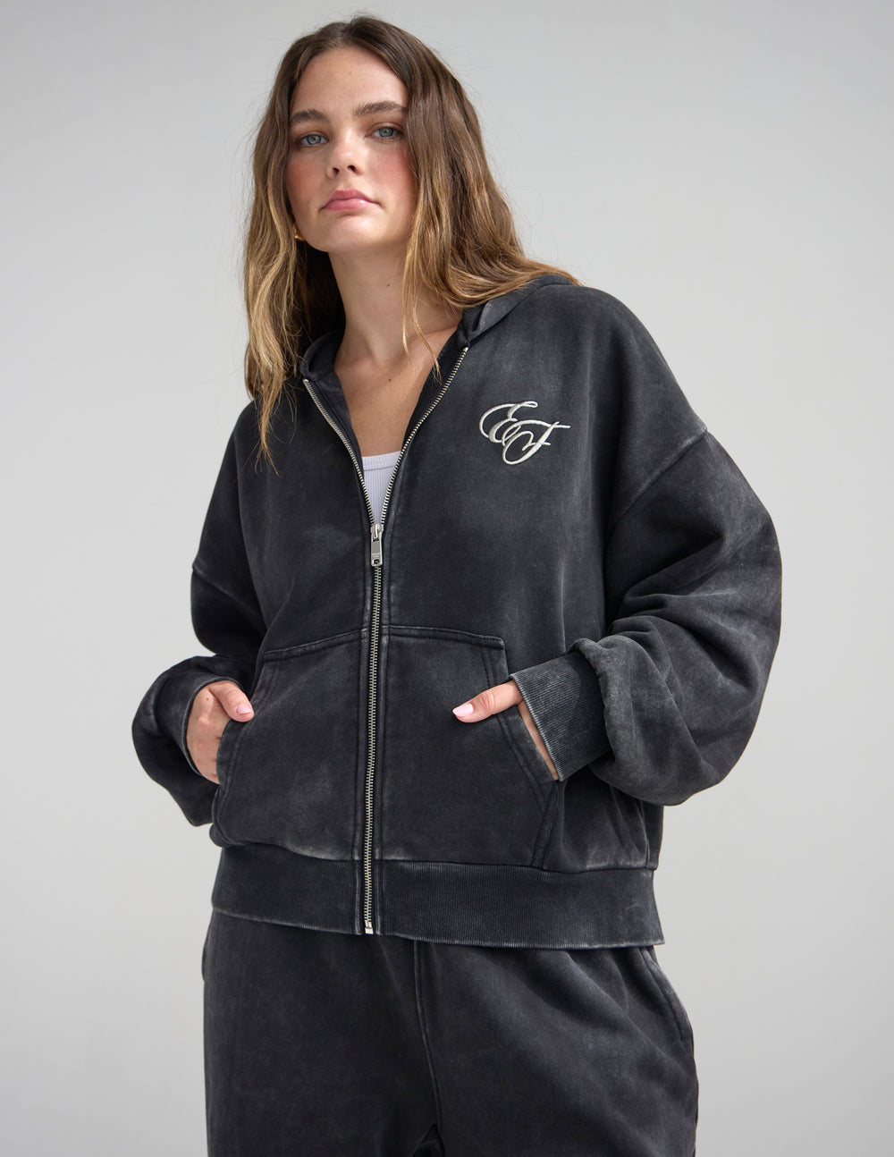 Dark charcoal full-zip hoodie with front zipper and cursive chest logo
