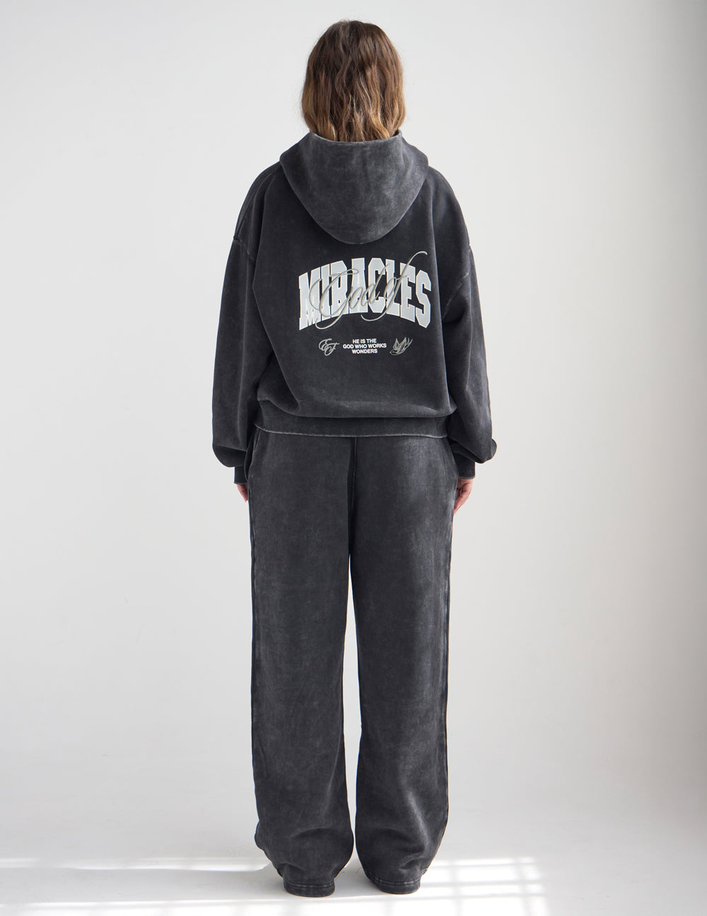 Dark charcoal full-zip hoodie with back wordmark under the hood