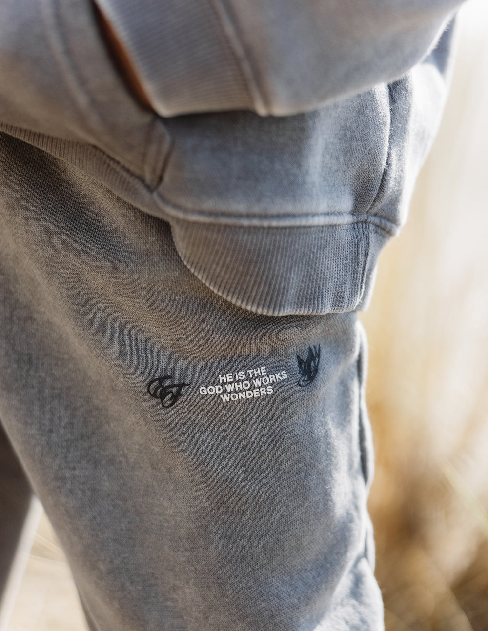 Kids grey sweatpants with small slogan logo on front leg