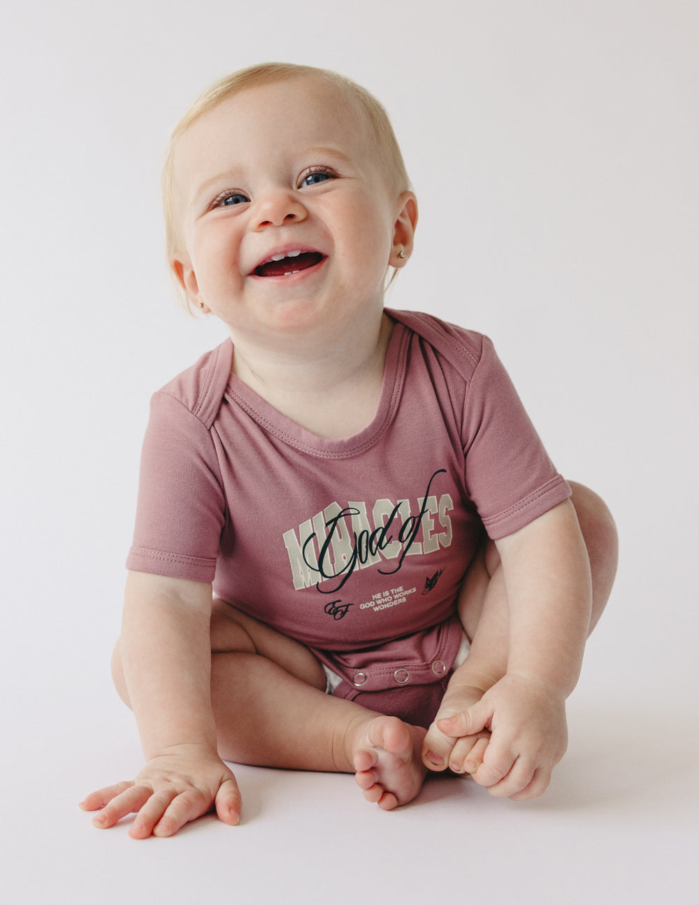 Mauve short-sleeve baby onesie with front graphic print and snap button legs