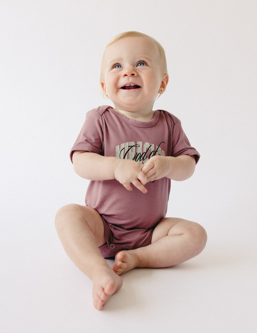Mauve short-sleeve baby onesie with front graphic and snap button crotch