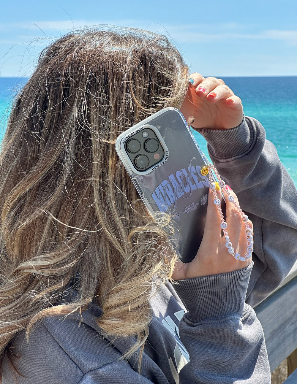 Gray phone case with blue “Miracles” graphic, shown in hand near camera lenses
