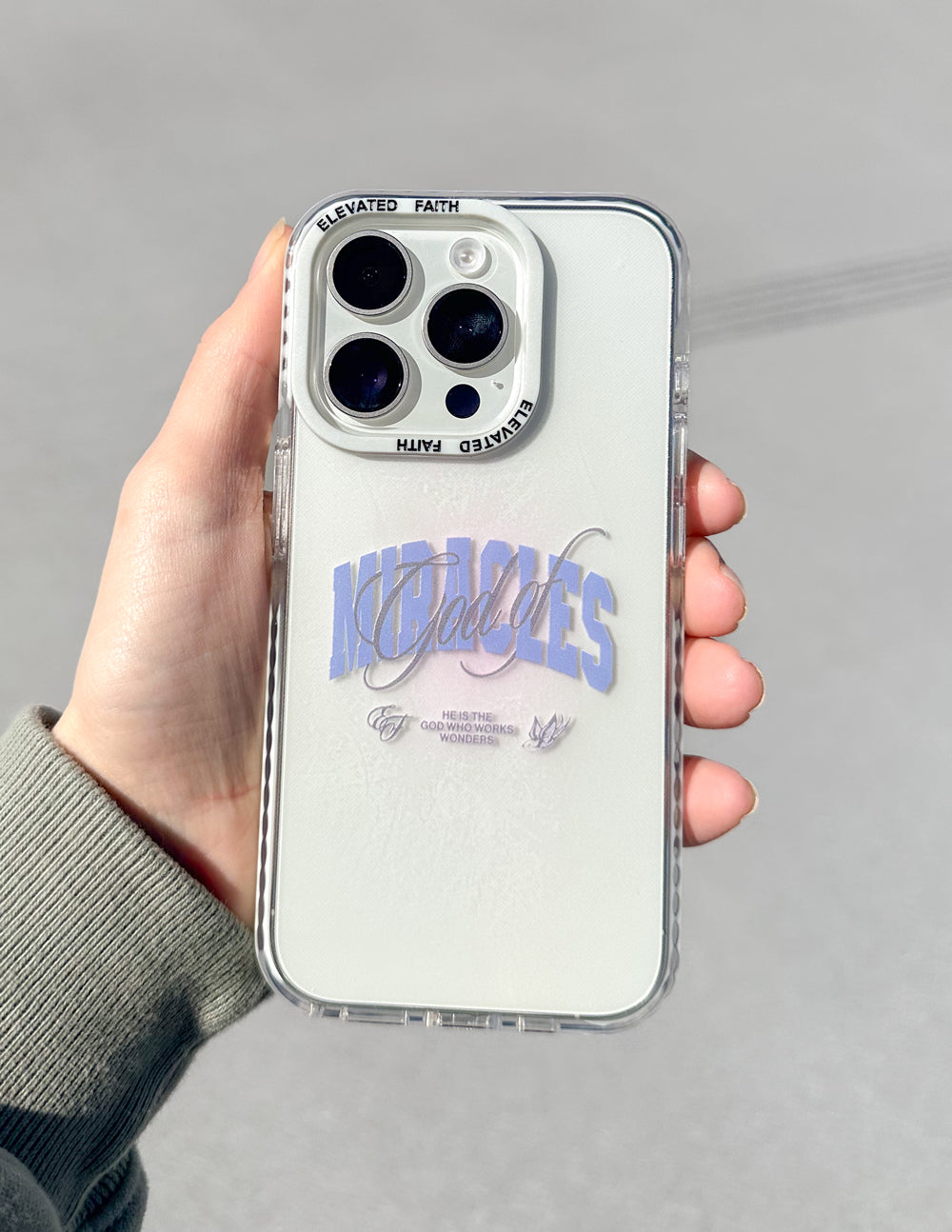White phone case with blue “Miracles” script and camera cutouts with clear rim