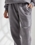 Dark gray unisex sweatpants with elastic waistband, tapered legs, side logo print
