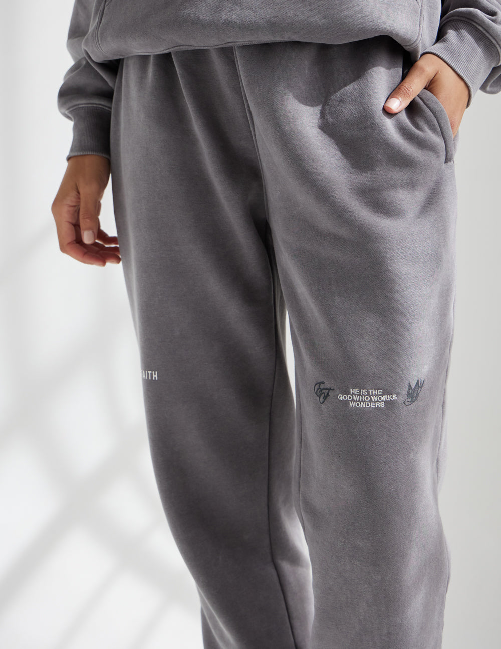 Dark gray unisex sweatpants with elastic waistband, tapered legs, side logo print